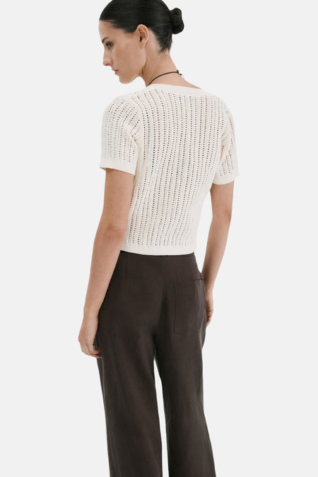 Wit ajourgebreid gilet van MANGO met korte mouwen, van achteren gezien op een model met donkere broek.