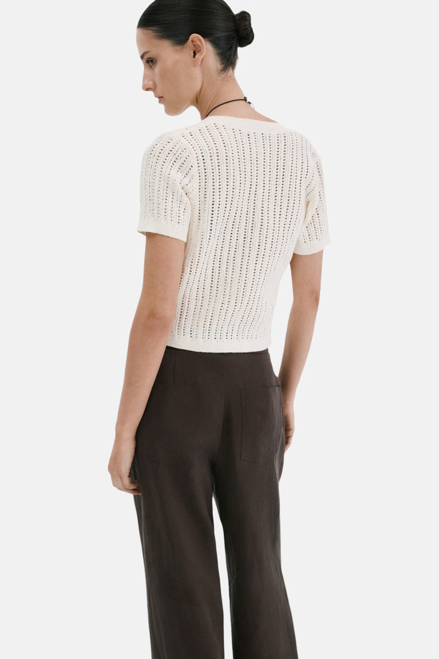 Wit ajourgebreid gilet van MANGO met korte mouwen, van achteren gezien op een model met donkere broek.