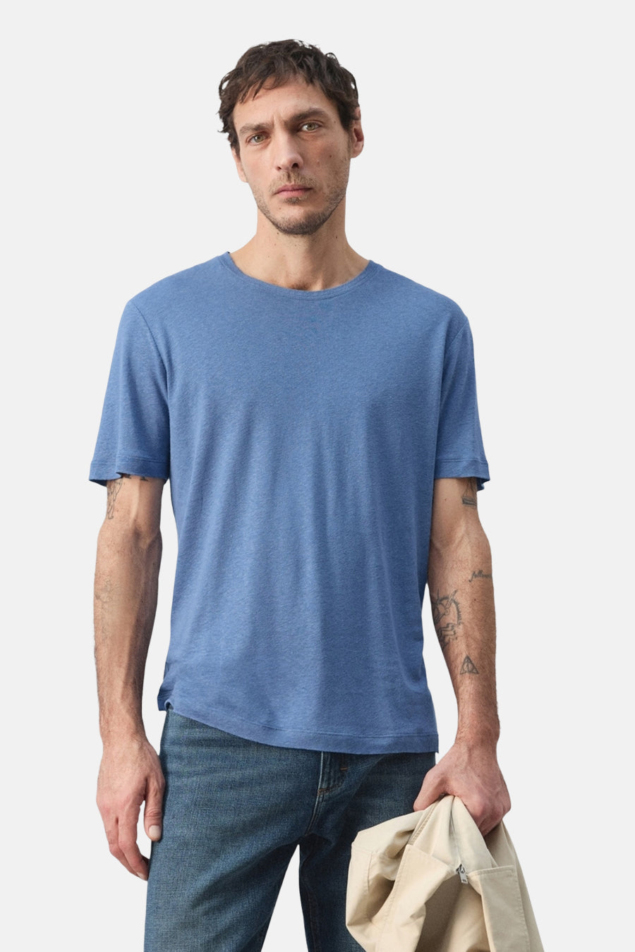 T-shirt bleu à manches courtes de MANGO, vu de dos, avec un jean et une veste à la main.
