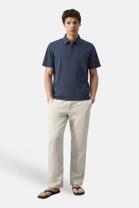 Polo bleue de MANGO à manches courtes, portée par un homme en pantalon clair, vue de dos.