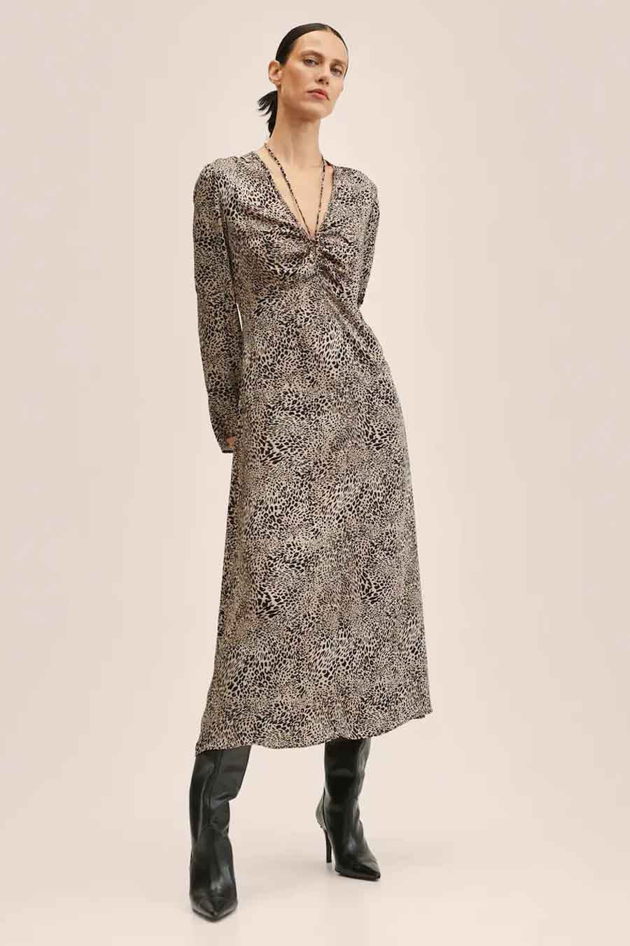 Robe longue beige de MANGO avec imprimé animal, col V et manches longues, associée à des bottes noires.