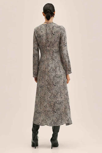 Robe beige de MANGO, avec imprimé léopard et longues manches, portée avec des bottes noires.
