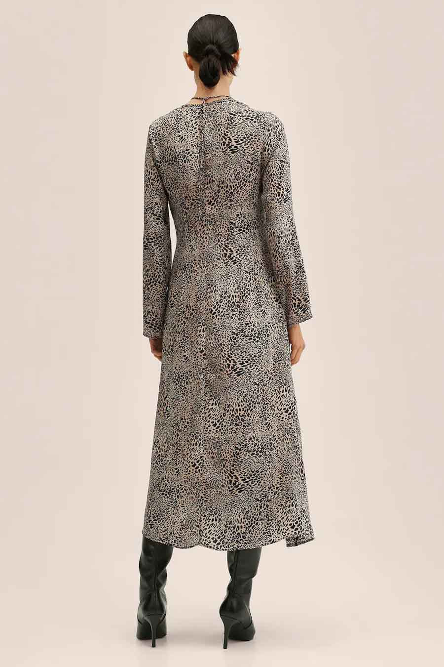 Robe beige de MANGO, avec imprimé léopard et longues manches, portée avec des bottes noires.