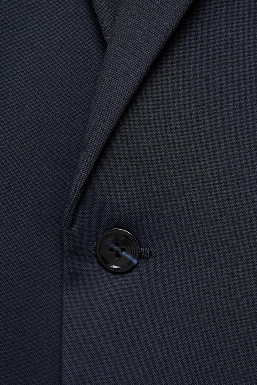 Blazer bleue de MANGO avec un tissu lisse et un bouton noir.