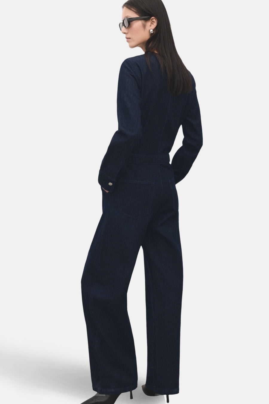 Combinaison de denim bleu marine de MANGO, avec des manches longues, des jambes larges et portée avec un chapeau de soleil.