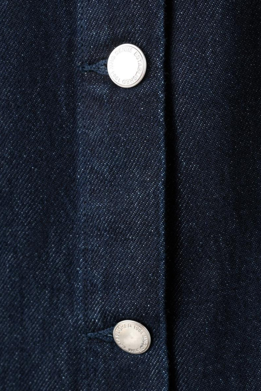 Combinaison de denim bleu marine de MANGO, avec des boutons argentés et une subtile texture de denim.