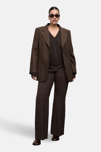 Gilet brun de MANGO, porté sous un blazer et associé à une jupe à imprimé à carreaux.