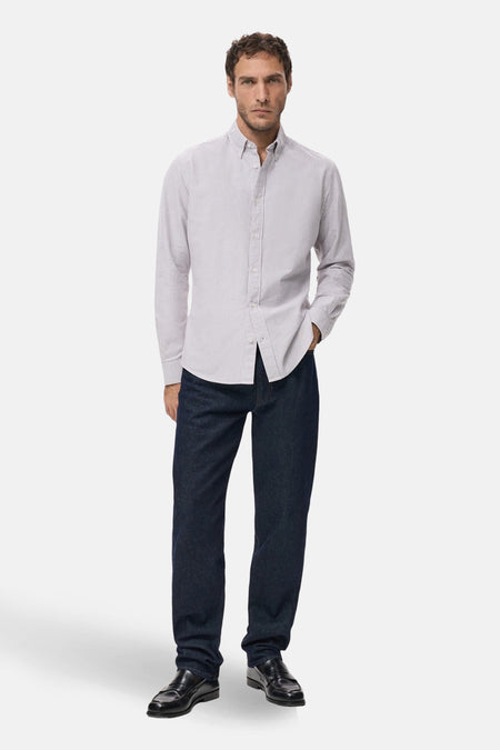 Man in gestreept overhemd, jeans en leren schoenen.