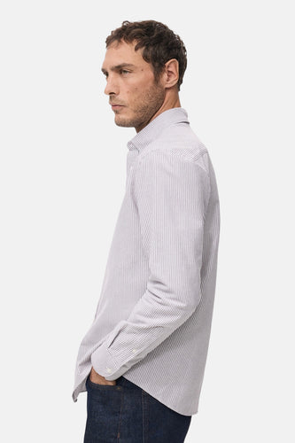 Man in gestreept overhemd en donkere jeans.