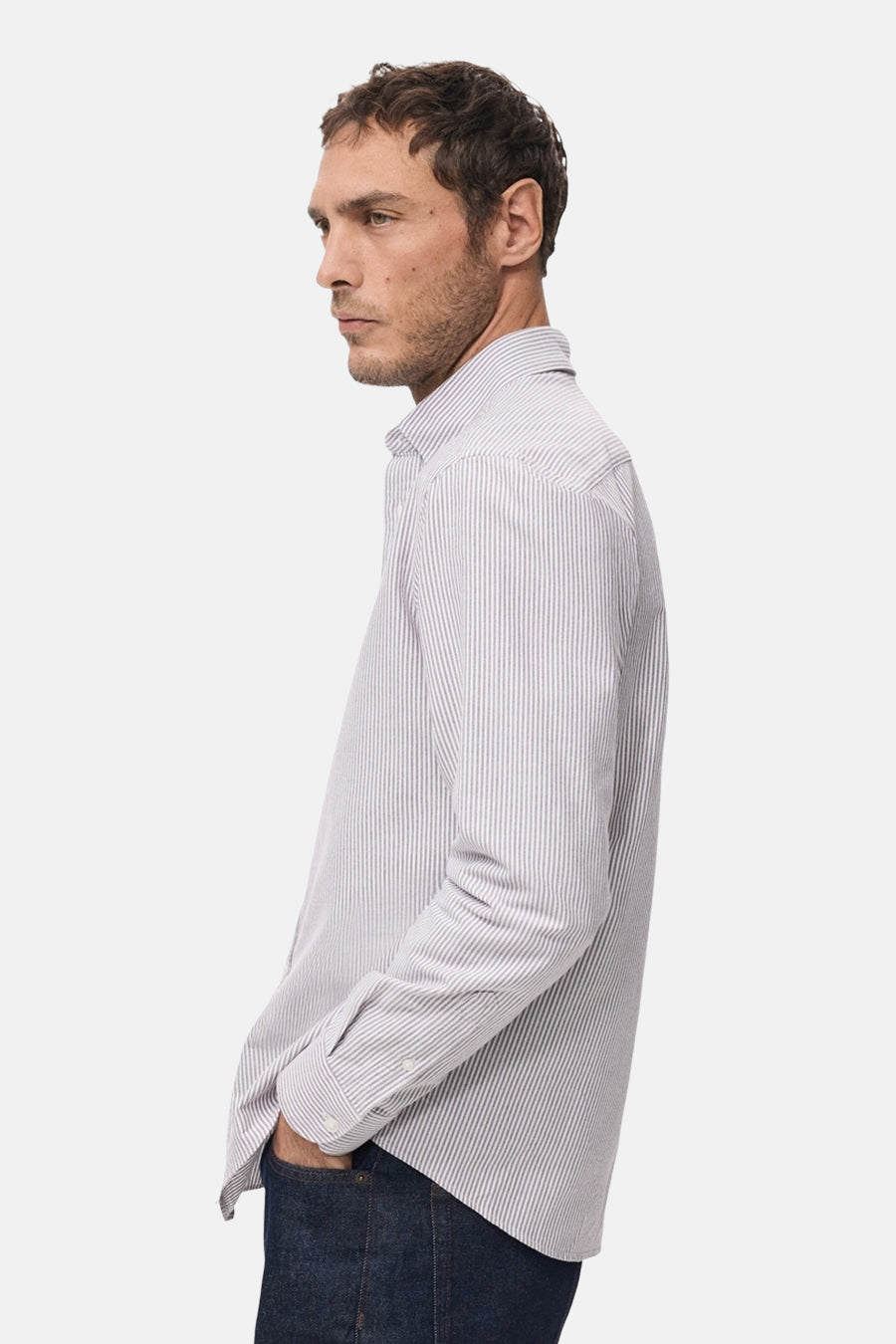 Man in gestreept overhemd en donkere jeans.