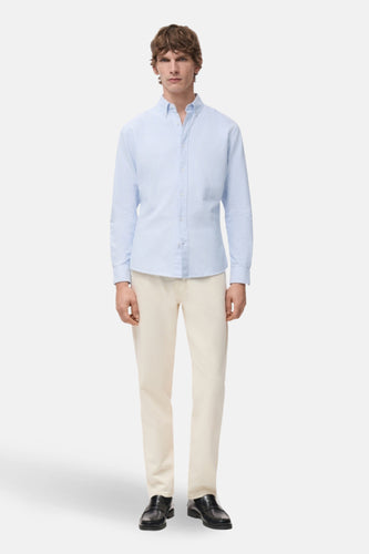 Man in blauw hemd, beige broek en zwarte schoenen.