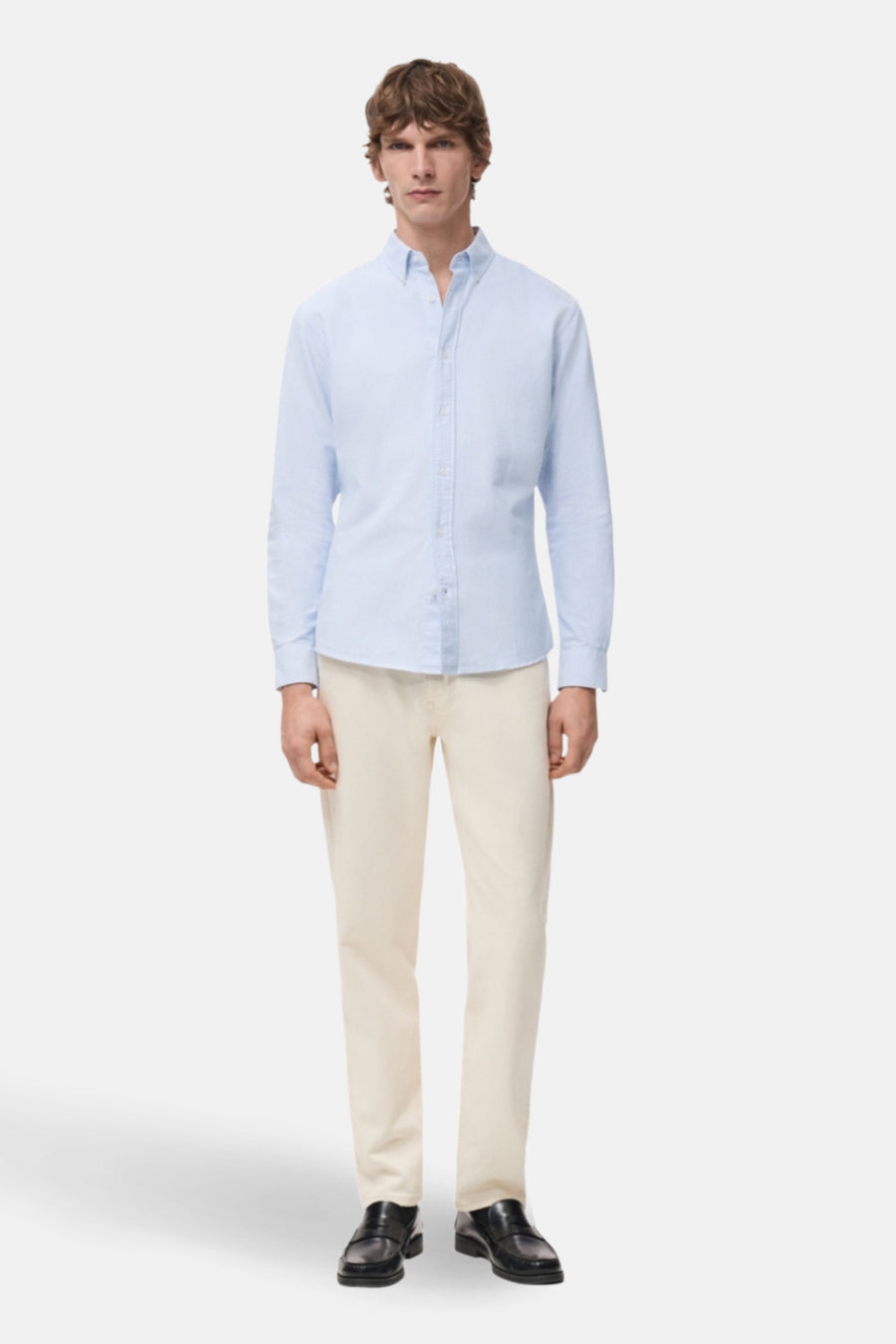 Man in blauw hemd, beige broek en zwarte schoenen.