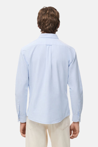 Achterkant van een persoon in gestreept lichtblauw overhemd en beige broek.
