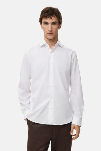 Blouse blanche à manches longues de MANGO, vue de derrière, associée à un pantalon marron.