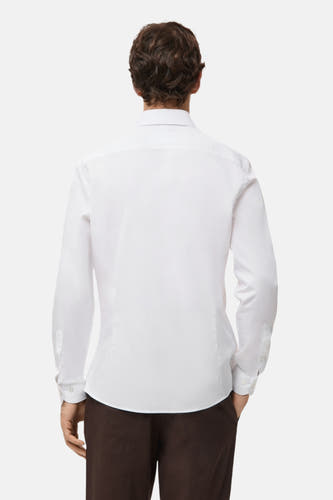 Wit overhemd met lange mouwen van MANGO, gezien van achteren, gecombineerd met een bruine pantalon.
