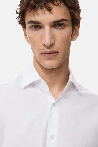 Chemise blanche à manches longues de MANGO, design simple avec col en V et fermeture à boutons.