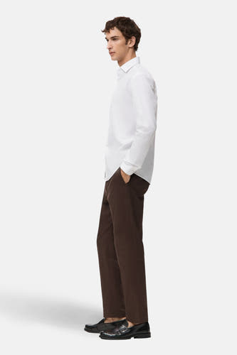 Blouse blanche à manches longues de MANGO, vue de côté, portée avec un pantalon marron et des chaussures noires.