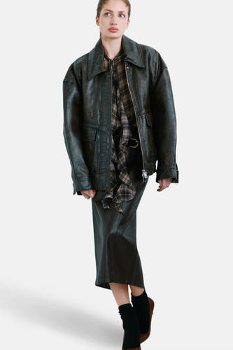 Blouse multicolore à manches longues de MANGO, avec un motif à carreaux et portée sous une veste en cuir noire et une jupe.