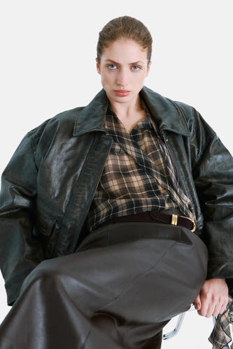 Blouse multicolore à manches longues de MANGO, avec un motif à carreaux et portée sous une veste en cuir.