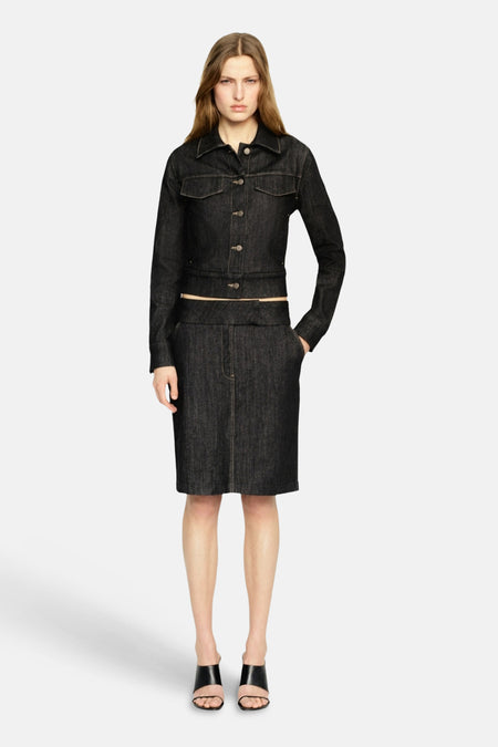 Veste en jean bleu foncé de MANGO, à manches longues et fermeture boutonnée, associée à une jupe assortie et des sandales noires.