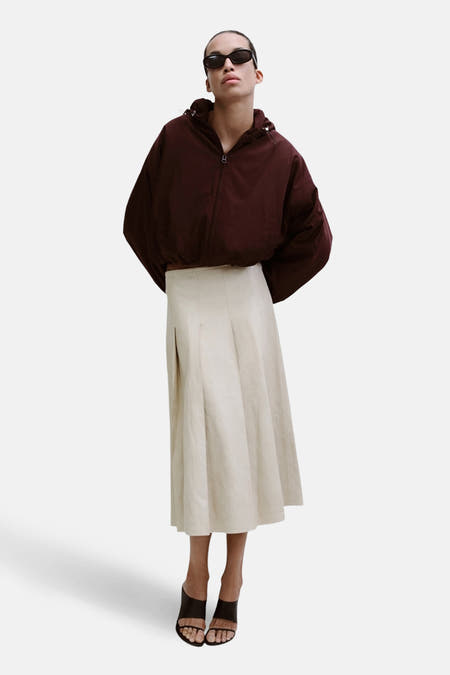 Lange beige rok van MANGO, gestyled met een donkerbruine jas en zwarte open schoenen.
