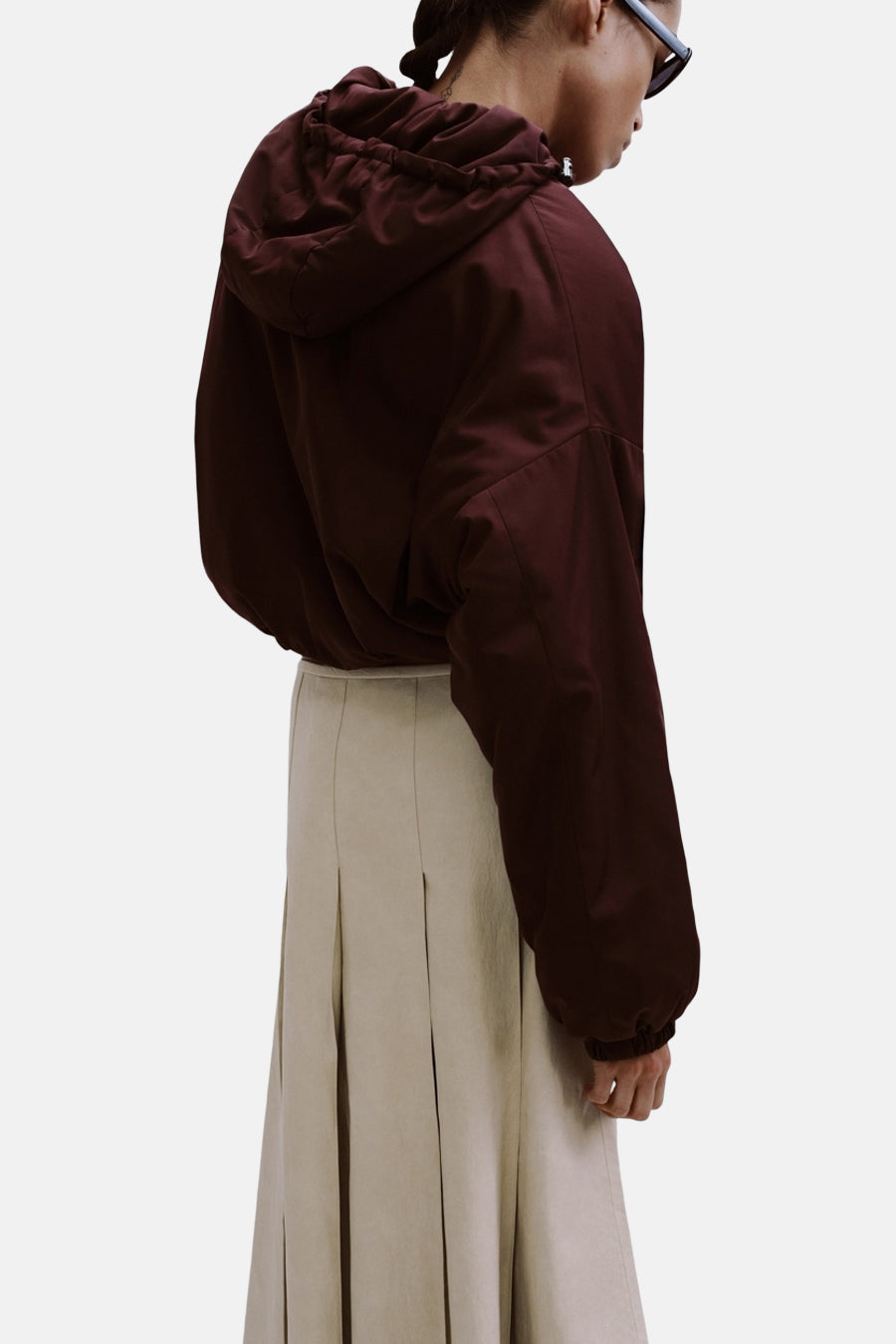 Lange beige rok van MANGO, met plooien en een lichte textuur, gecombineerd met een bordeauxrode jas met capuchon.