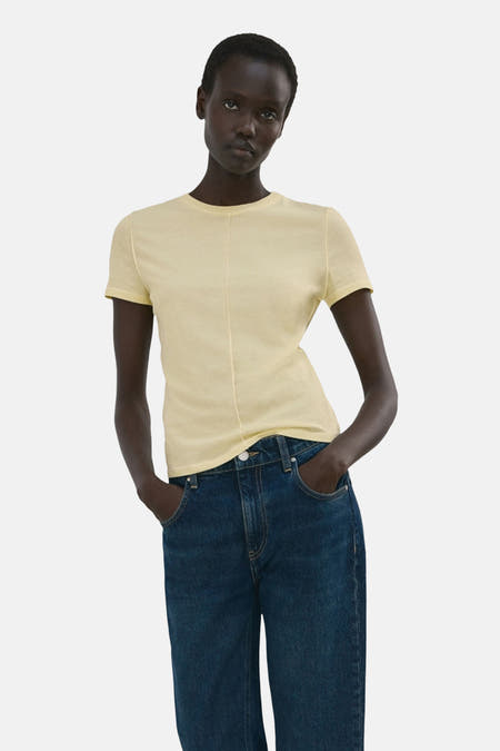 Geel T-shirt met korte mouwen van MANGO, met een verticale naad aan de voorkant, gedragen met een donkere spijkerbroek.