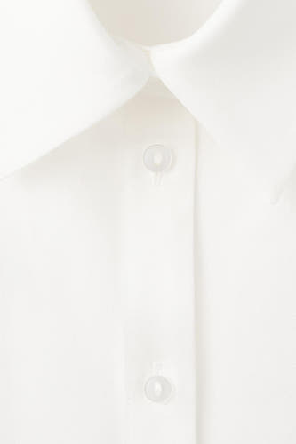 Chemise blanche à manches longues de MANGO, avec fermeture boutonnée et col classique.