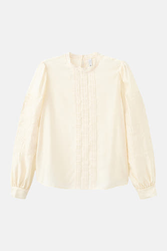 Blouse écru à manches longues de MANGO, finie avec des détails en dentelle et des broderies florales sur les manches.