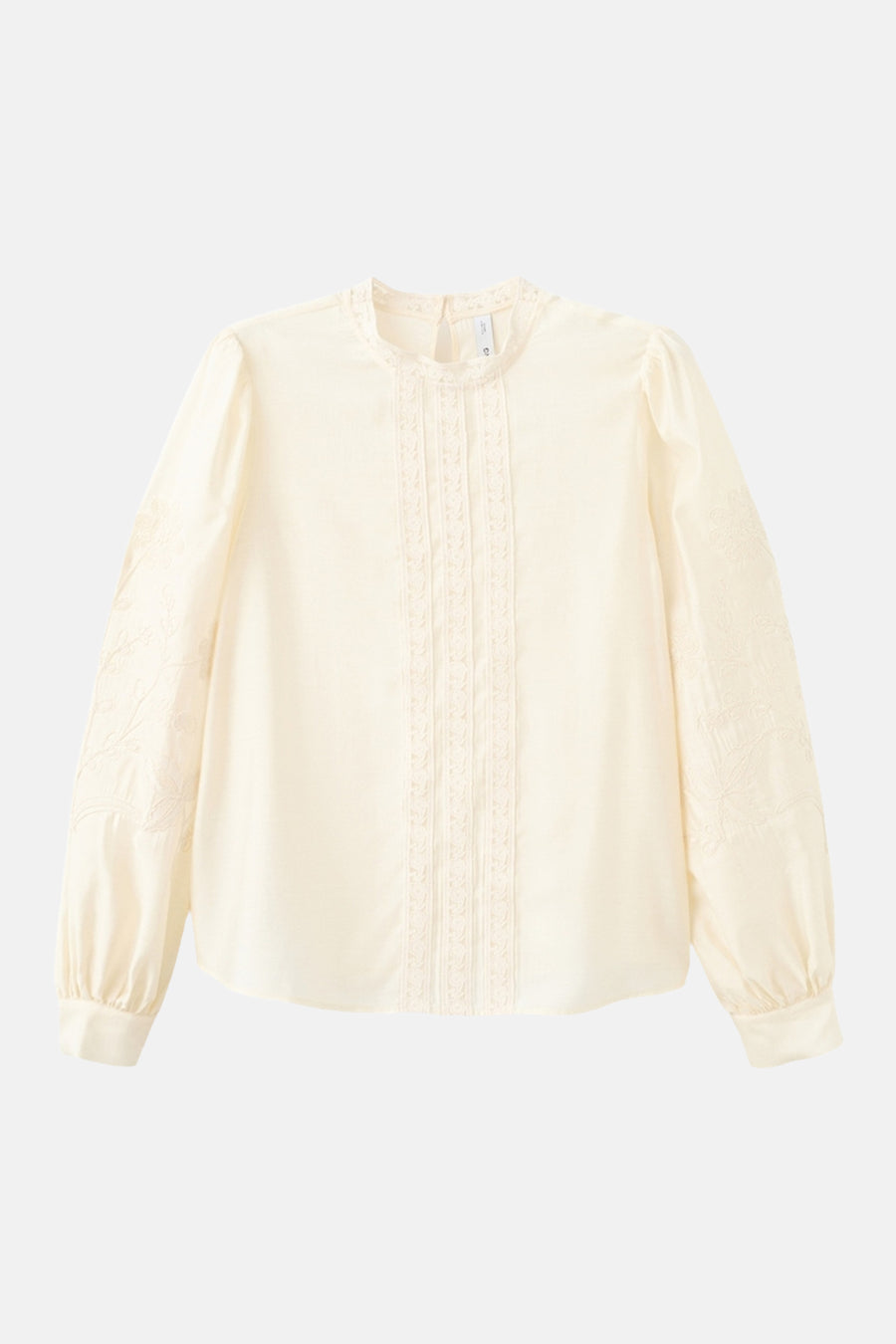 Blouse écru à manches longues de MANGO, finie avec des détails en dentelle et des broderies florales sur les manches.