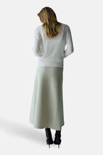 Gilet écru de MANGO, vu de dos, combiné avec une longue jupe et des bottines noires à talons.