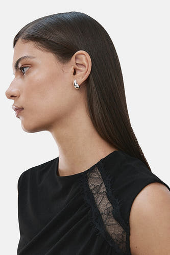 Chemisier noir sans manches de MANGO, avec détails en dentelle sur le côté, porté par une femme de profil.