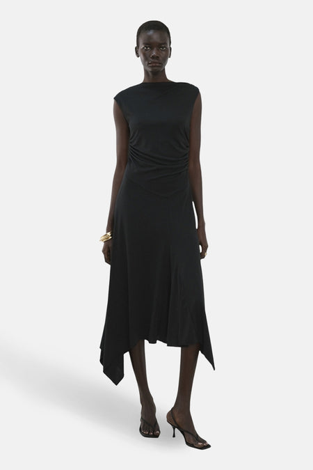 Robe noire sans manches de MANGO, avec un ourlet asymétrique et un bracelet doré.