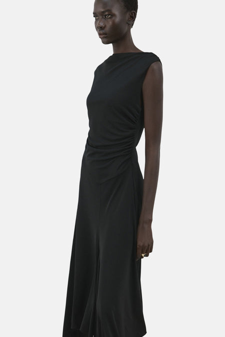 Robe noire sans manches de MANGO, avec détail drapé sur le côté et jupe évasée.