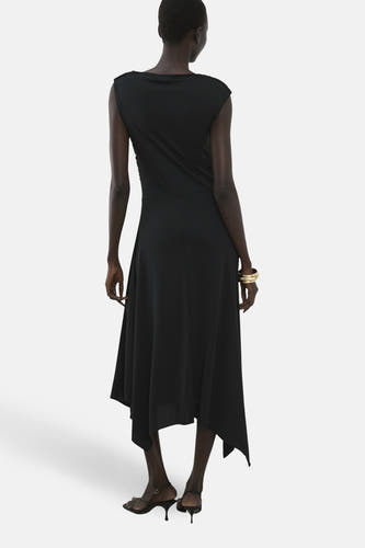 Zwarte mouwloze kleedje van MANGO, met een asymmetrische zoom en gouden armband.