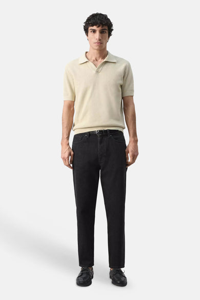 Beige korte mouwen polo van MANGO, met fijne textuur, gedragen met zwarte jeans en schoenen, front view.