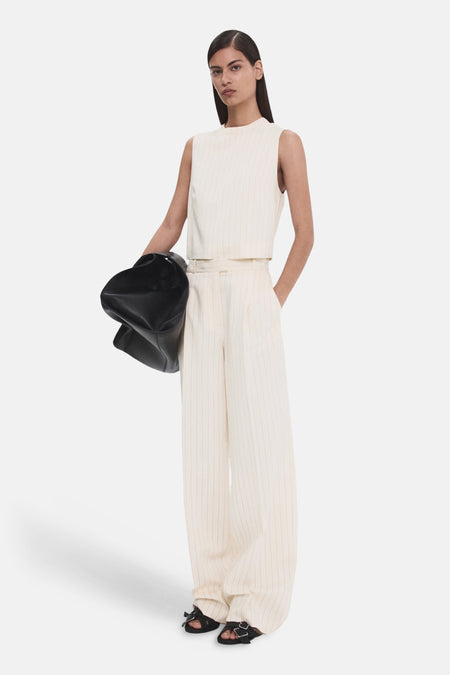 Pantalon blanc MANGO à rayures craie, jambes larges, porté avec un haut assorti et des sandales noires.