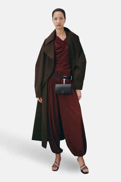 Pantalon marron de MANGO, à jambes larges et associé à un long manteau et une ceinture avec pochette.