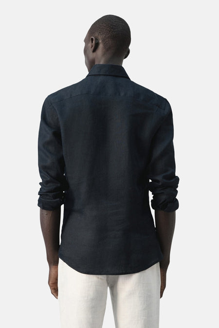 Blauw overhemd met lange mouwen van MANGO, gezien van achteren met een effen textuur en witte broek.
