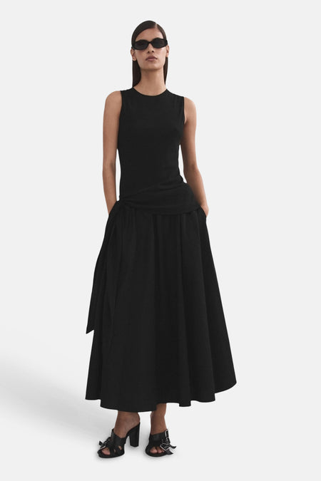 Jupe longue noire de MANGO avec taille plissée, poches et un détail de nœud sur le côté.