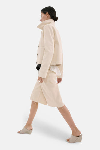 Bermuda de couleur jaune clair de MANGO avec jambes larges et ourlets effilochés, portée de profil par un mannequin.