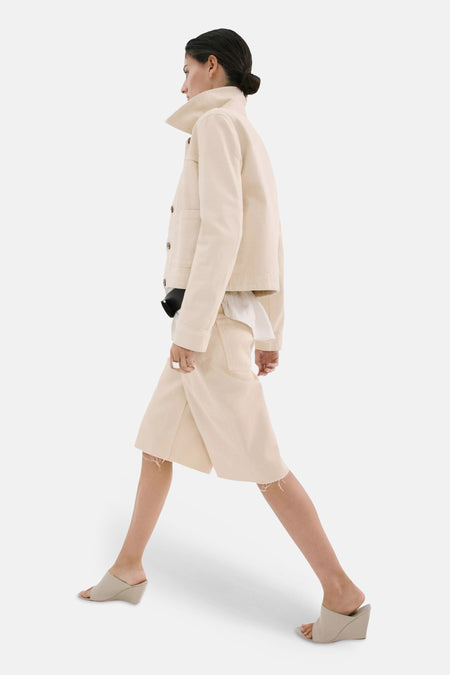 Bermuda de couleur jaune clair de MANGO avec jambes larges et ourlets effilochés, portée de profil par un mannequin.