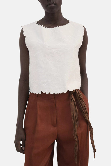 T-shirt blanc de MANGO avec bords festonnés, porté à l'arrière avec un pantalon marron.