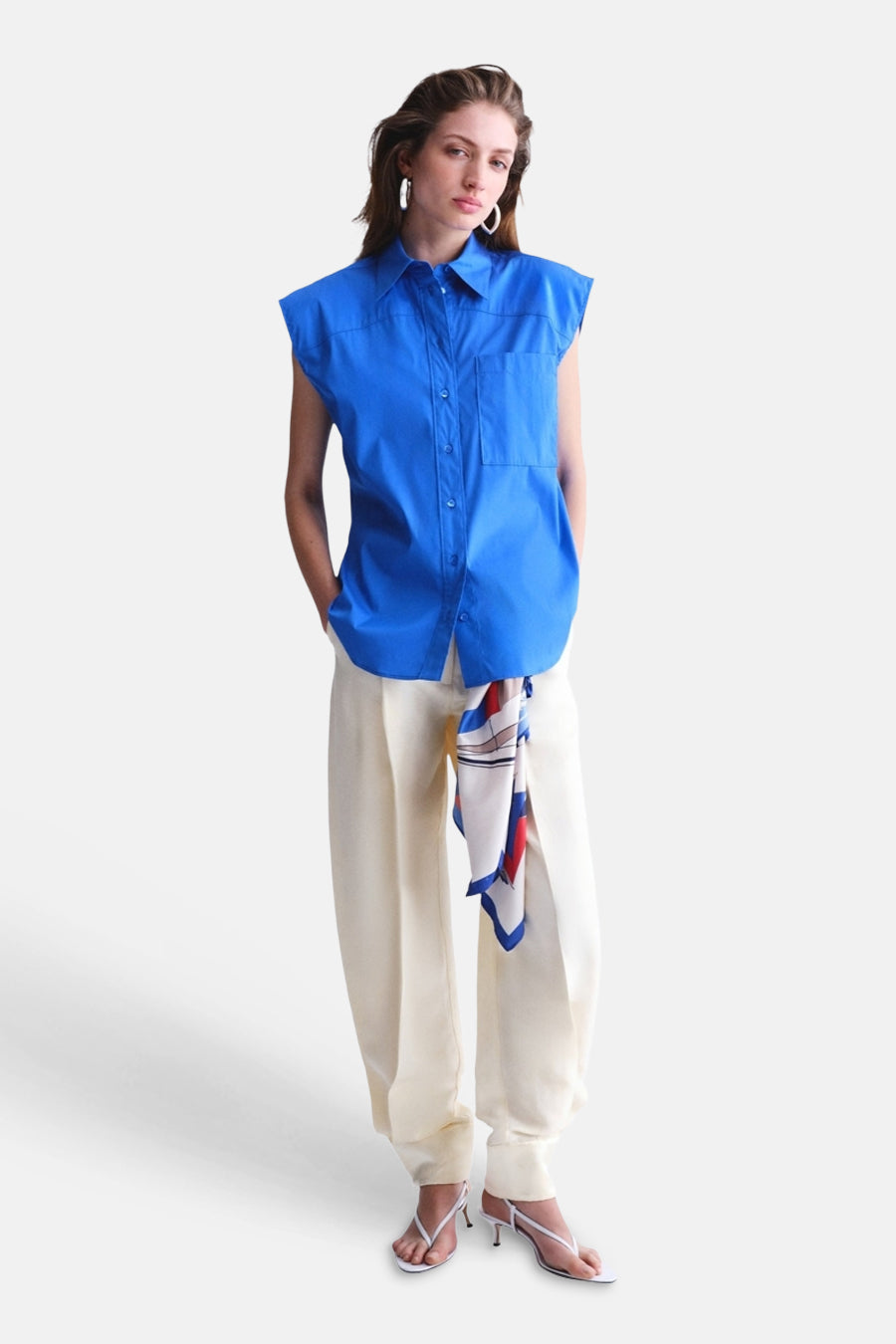 Chemise sans manches bleue de MANGO avec col et poches, combinée avec un pantalon de couleur crème.