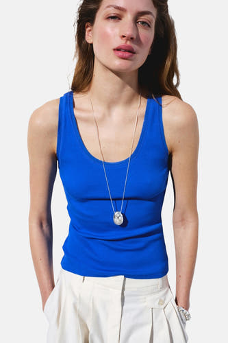 Débardeur côtelé bleu de MANGO, vu de dos sur mannequin avec pantalon blanc et bracelet.