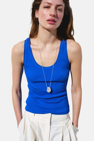 Débardeur côtelé bleu de MANGO, vu de dos sur mannequin avec pantalon blanc et bracelet.