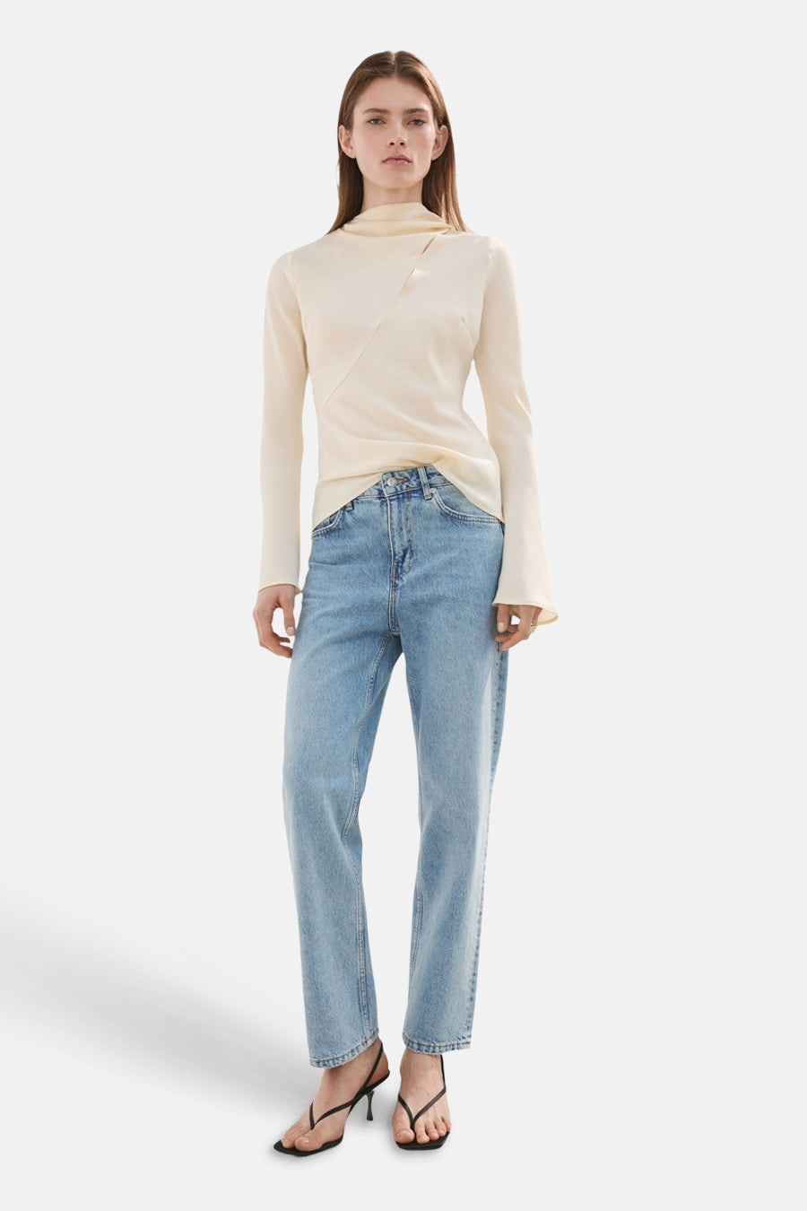 Jean droit en denim bleu clair de MANGO, associé à un haut écru et des talons noirs.
