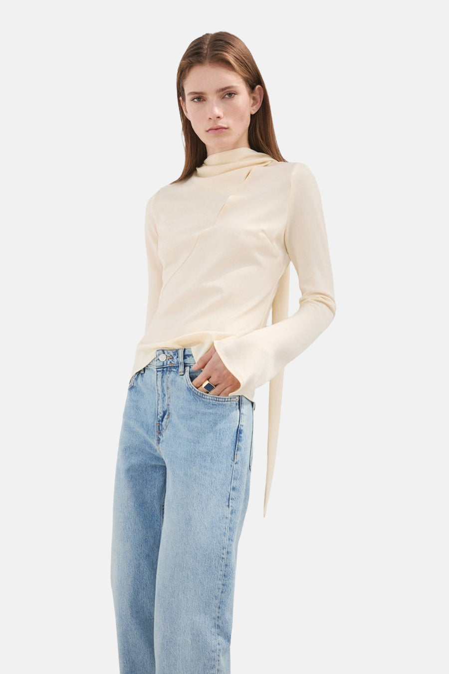 Jean droit MANGO en denim bleu clair, porté avec un haut crème à manches longues et une bague remarquable.