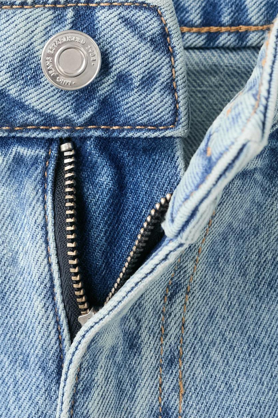 Jeans coupe droite en denim bleu clair de MANGO, avec fermeture éclair ouverte et bouton argenté.