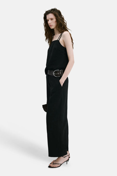 Pantalon noir MANGO à jambes larges, vu de côté sur un mannequin portant un haut noir et une large ceinture.